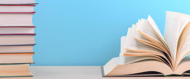 istock The book is open, the sheets are fan-shaped on a blue background next to a stack of books. 1262085439