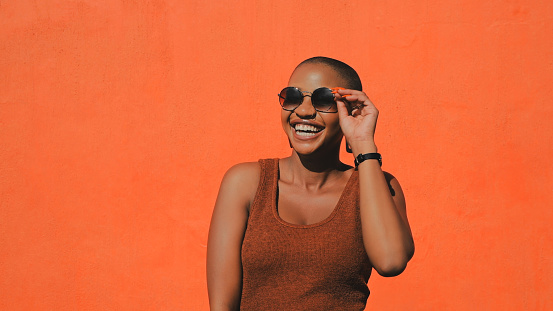 Shot of an attractive young woman posing against an orange wall outdoors