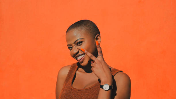 V is for very happy Shot of an attractive young woman making a peace gesture against an orange wall outdoors shaved black women stock pictures, royalty-free photos & images