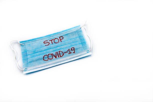 istock Single use medical face mask with handwritten message Stop Covid-19 isolated over white background, coronavirus protection concept 1262151120
