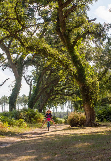 istock Pretty young girl riding a bicycle in the forest 1262171941