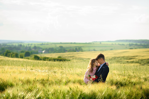 Father and daughter in a green wheat field.