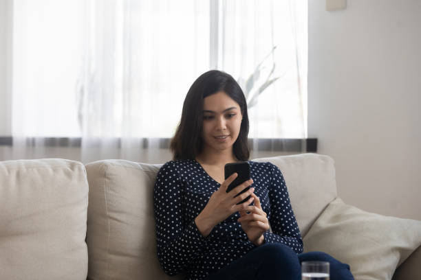 istock Millennial Asian girl relax on couch browsing smartphone 1262199068