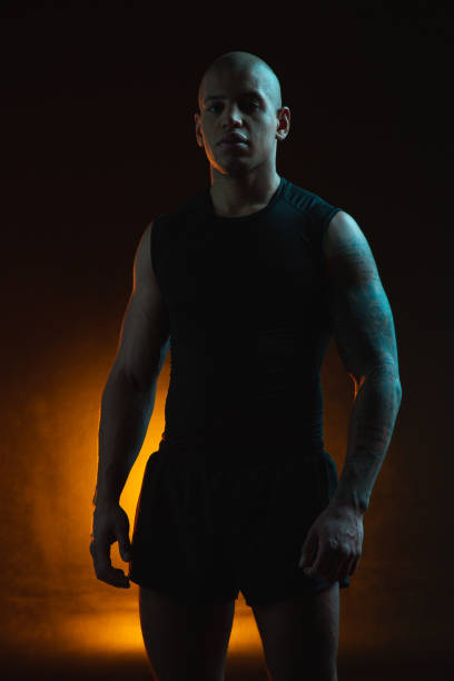 istock Handsome athlete posing in sports clothes in dark studio 1262199118