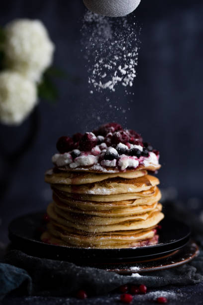 istock Stack of pancakes with sugar powder splashes on dark background table. 1262200740