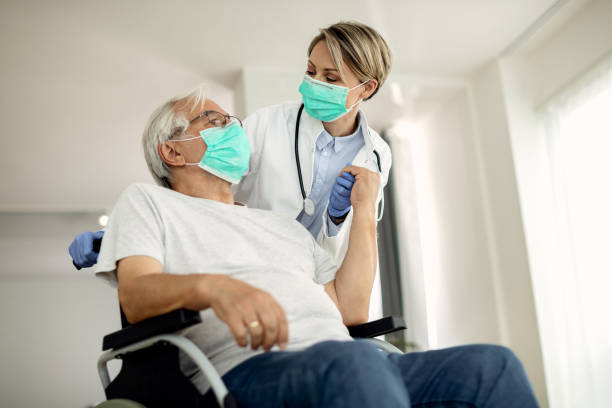 You know that I will always take care of you! Below view of female doctor holding hands with senior man in wheelchair while visiting him at home during coronavirus lockdown. medical supplies wheelchair medical equipment nursing home stock pictures, royalty-free photos & images