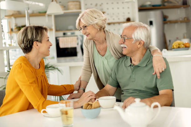 Happy mature couple talking to their adult daughter at home. Happy woman visiting her senior parents and communicating with them at home. family reunion stock pictures, royalty-free photos & images