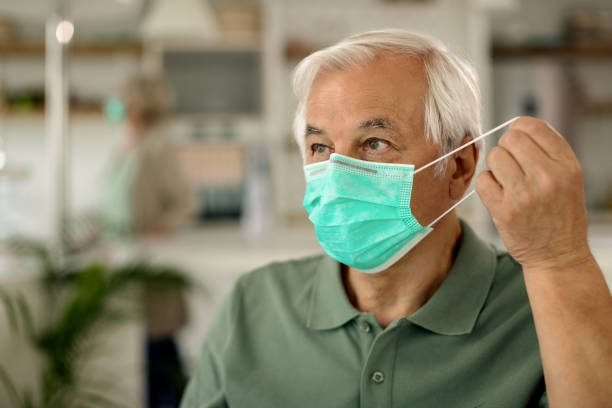 istock Senior man putting on protective face mask during COVID-19 epidemic. 1262236412
