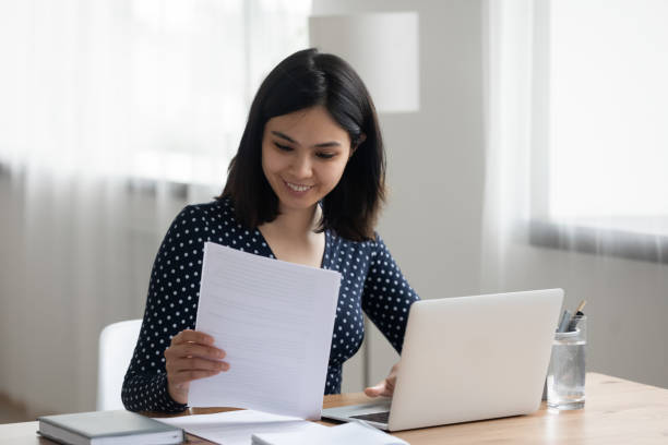 istock Smiling Asian girl work on laptop reading documents 1262241410
