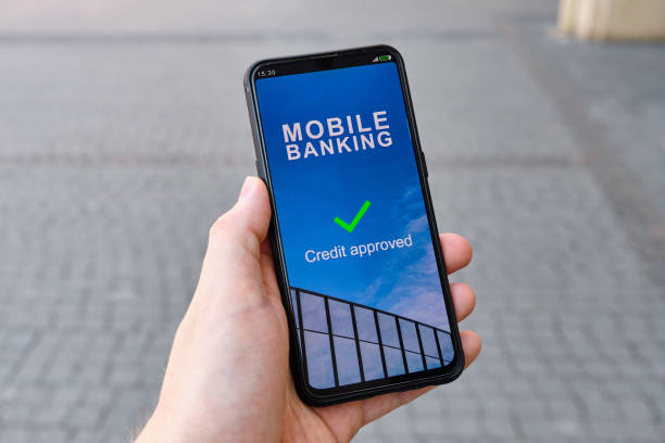 istock Hand holds smartphone with mobile banking interface credit approved 1262257362