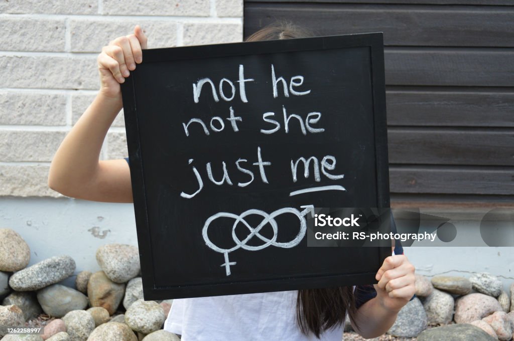 Confident teenager gives important message about being happy with your own gender identity Teenager identifying as non-binary is holding a black signboard with handwritten text and symbol related to gender identity Non-Binary Gender Stock Photo