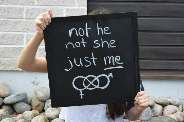 Confident teenager gives important message about being happy with your own gender identity Teenager identifying as non-binary is holding a black signboard with handwritten text and symbol related to gender identity non binary gender stock pictures, royalty-free photos & images
