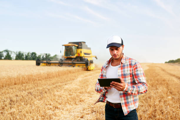 Precision farming. Farmer holding tablet for combine harvester guidance, control with modern automation system. Agronomist using online data management software generating yield maps at wheat field agricultura de precisión. tableta de retención de agricultores para la guía y el control de la cosechadora combinada con el sistema de automatización moderno. agrónomo que utiliza software de gestión de datos en línea que genera mapas de rendimiento
