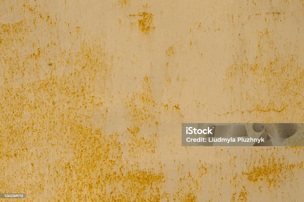 Texture of rusty corrosive metal fence, with flattened yellow paint from dilapidation. Rusty non ferrous metal. Cracks of yellow paint from weathering on the surface of the metal sheet. An abstract rusty metal textural surface of yellow color with cracks, like a vintage metal background with the ability to insert text. Metal corrosion Abstract Stock Photo