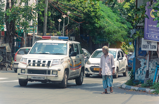 Kolkata, 07/26/2020: An aged person without wearing a face mask, is looking at a passing Kolkata Police patrol van in street. Though mandatory, many people are seen casually not wearing masks.