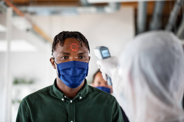 istock Businessman getting his temperature checked in office by sanitation worker 1262271975