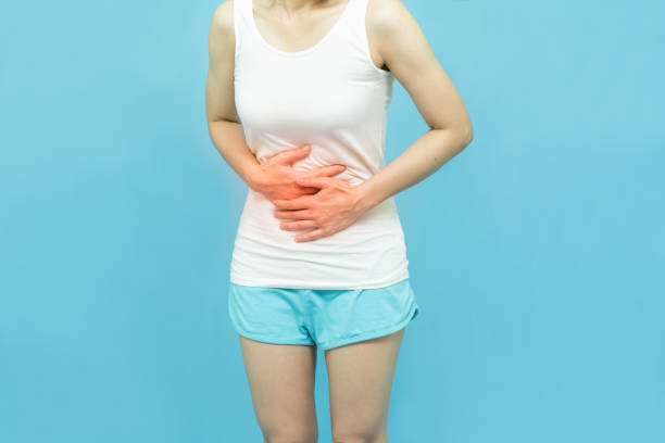 le corps bas d’une femme dans le dessus blanc de réservoir a mis ses mains sur la zone d’estomac marque rouge à la tache de douleur, douleur abdominale, concept de soins de santé sur le fond blanc - mental health women asian ethnicity bicycle photos et images de collection