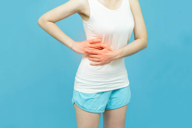 le corps bas d’une femme dans le dessus blanc de réservoir a mis ses mains sur la zone d’estomac marque rouge à la tache de douleur, douleur abdominale, concept de soins de santé sur le fond blanc - mental health women asian ethnicity bicycle photos et images de collection