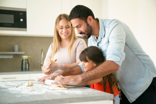 istock Happy young parents teaching daughter to roll dough 1262274388