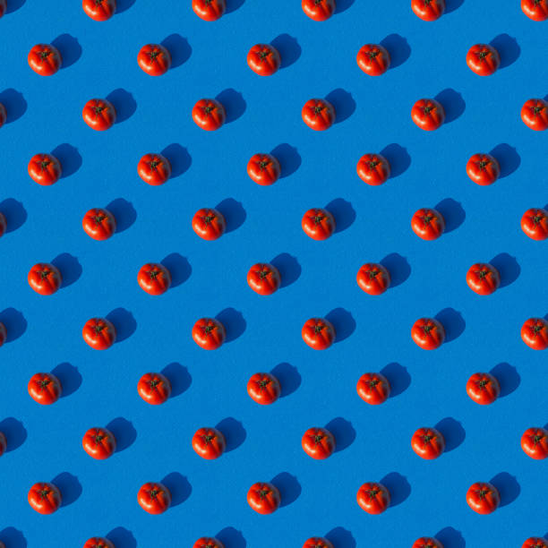 istock Pattern of red tomatoes on a blue background. Seamless texture. 1262277350
