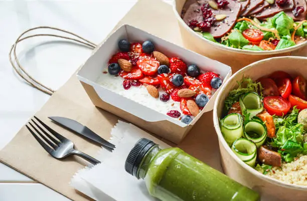 Photo of Healthy meal slimming diet plan daily ready menu background, organic fresh dishes and smoothie, fork knife on paper eco bag as food delivery courier service at home in office concept, close up view.