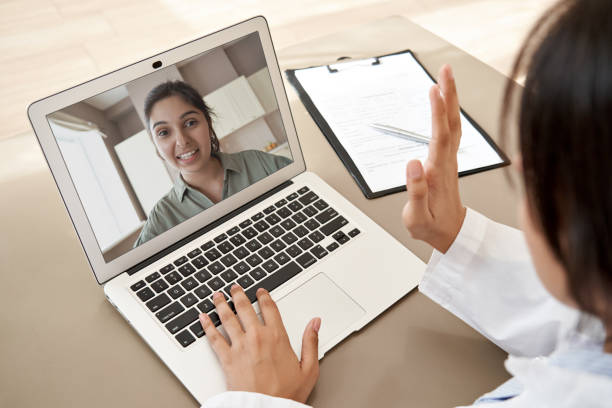 Female doctor gp consulting indian woman patient make online webcam video call on laptop screen. Telemedicine conference remote computer virtual visit in meeting. Over shoulder videocall view. mujer médico gp consultando mujer india paciente hacer videollamada webcam en línea en la pantalla del ordenador portátil. conferencia de telemedicina visita virtual de computadora remota en reunión. sobre la vista de videollamada de hombro.
