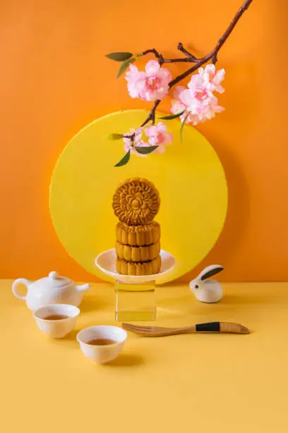 Stylised Mid autumn festival food, mooncake, decorative items and tea set on coloured  background.