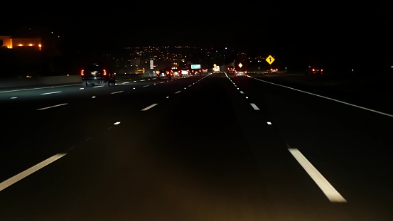 View from the car. Los Angeles busy freeway at night time. Massive Interstate Highway Road in California, USA. Auto driving fast on Expressway lanes. Traffic jam and urban transportation concept