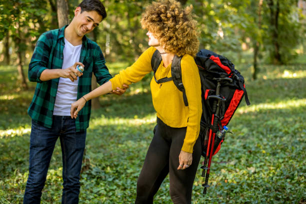 homme utilisant le jet anti-moustique à l’extérieur au voyage de randonnée. plan rapproché de jeune touriste de routard féminin appliquant le jet d’insecte sur des mains - insect repellant mosquito bug bite spraying photos et images de collection