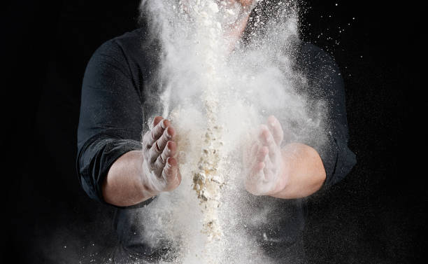 istock chef in black uniform sprinkles white wheat flour in different directions, product scatters dust 1262289920