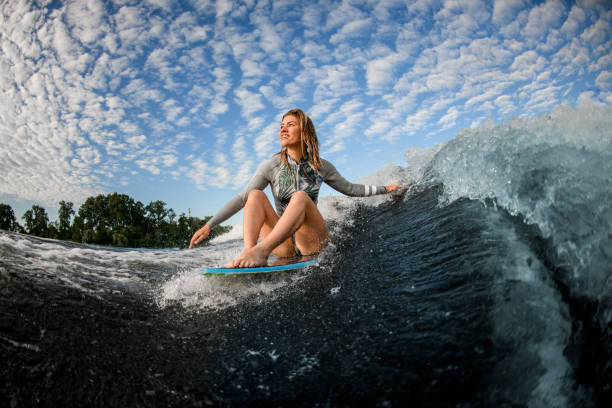 istock cheerful blond woman riding the waves while sitting on wakesurf board 1262291213