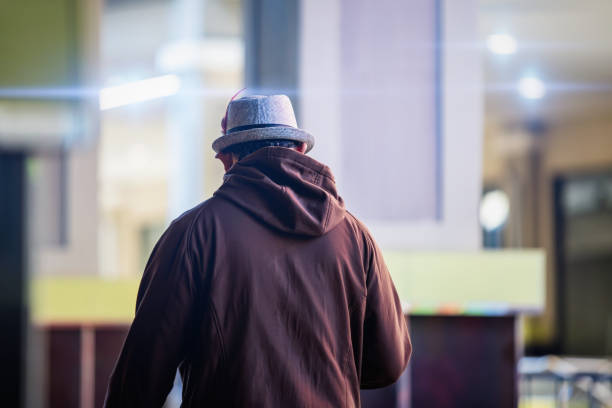 african man with a feather on his hat walking in a shopping mall