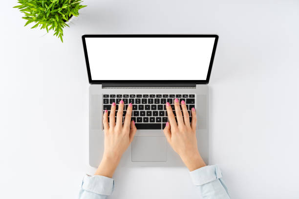 istock Woman’s hands working on laptop with empty screen on white background. Office desktop with accessories. Top view 1262293919