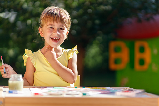 Happy young girl holding a paint brush and smiling