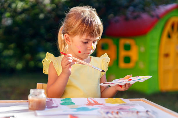 istock Serious young child frowning when using paint brush and paint palette 1262294093