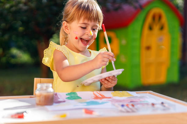 istock Playful girl using paint brush and paint palette 1262294098