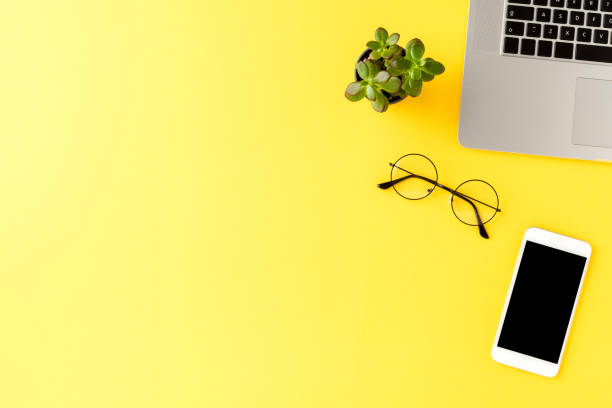 istock Elegant office desktop with business accessories on yellow background with copyspace. Top view 1262294110