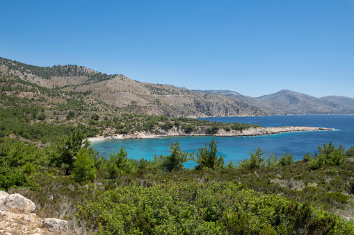 A deserted Greek Island beach in the summer of 2020 during the COVID-19 pandemic. This beautiful beach, the Tigani Beach, on the west coast of Chios Island in the Aegean Sea is usually populated by crowds of tourists on any sunny day at this time of year. However, this year tourists (from European countries, as well as the US) are generally advised against, or even prohibited from, travel abroad. Thus, miles and and miles of beaches are largely empty, on Chios (as well as other popular travel destinations in Greece). The only exceptions (of desertion of Chios beaches) are a few beaches that are offering food and drinks (by tavernas at, or close to, the beach), that still get visited by the local population during weekends (by social distancing).