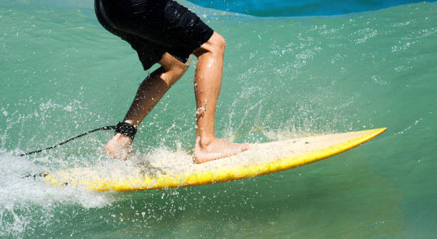 istock Surfers legs on yellow surfboard in aqua water 1262294575