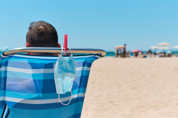 istock mask and man sitting in a deck chair on the beach 1262294727