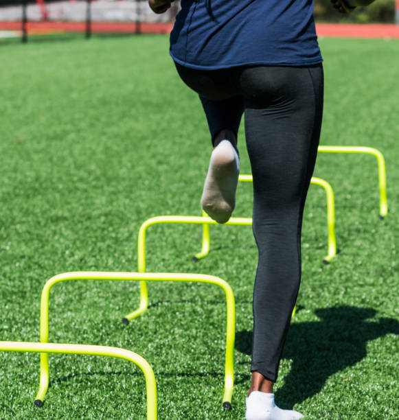 istock Athlete stepping over yellow mini hurdles on turf field 1262294820