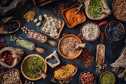 Top view low key of a large variety of dry beans. Shot from above on rustic wooden table