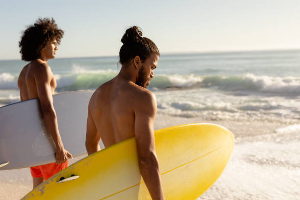 istock Multi-ethnic males holding surfboards on the beach 1262296040
