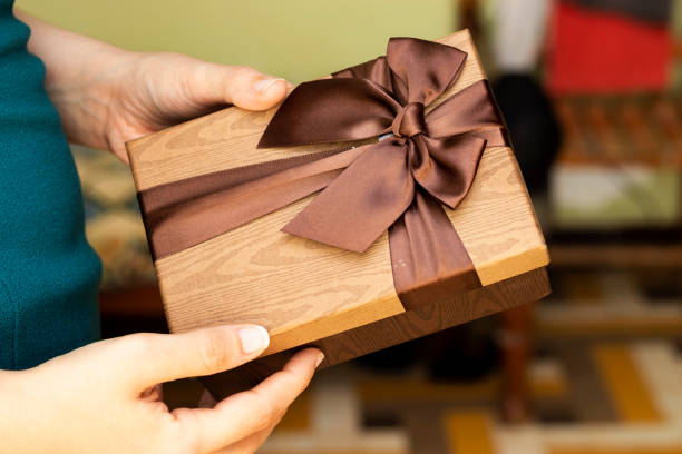 istock Hand Holding Gift In Package With brown Ribbon, holidays concept 1262298588