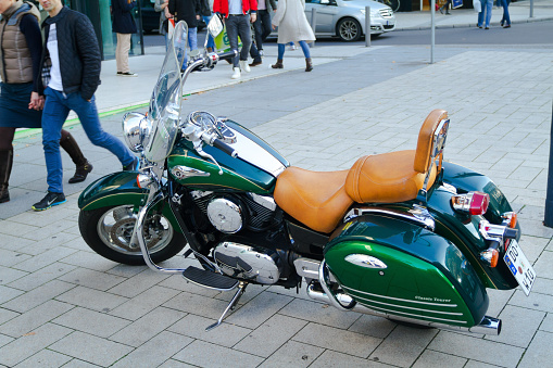 Green kawasaki motorcycle parked in Dortmund in pedestrian zone. A few people are walking in left area