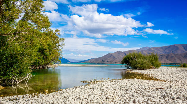 The slow flowing Pukaki river as it flows into Lake Benmore on a sunny day Landscape of the slow flowing Pukaki river as it flows into Lake Benmore, with mountains in the background, Twizel, New Zealand omarama stock pictures, royalty-free photos & images