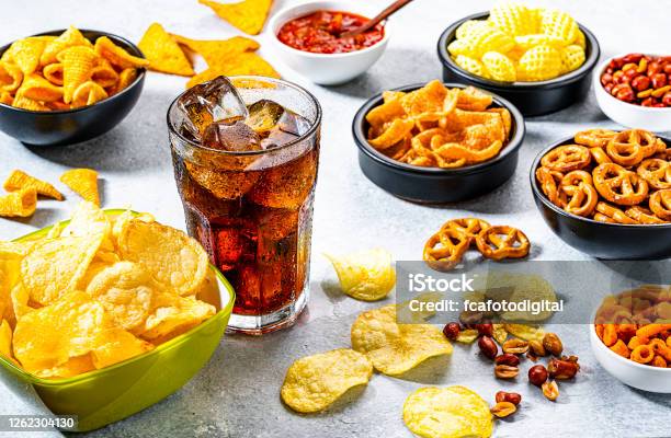 Cola Soda Glass And Salty Snacks Shot On Gray Table Stock Photo - Download Image Now