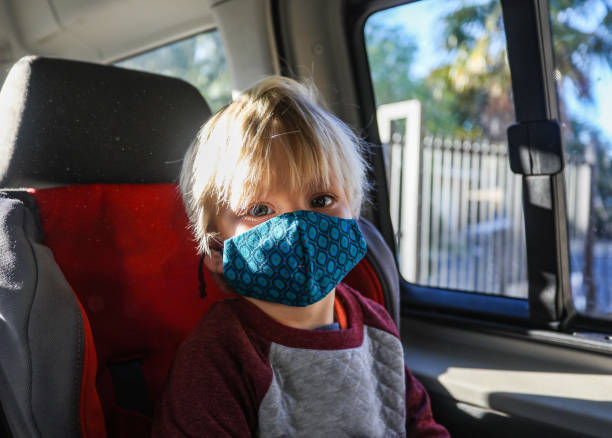 istock A boy with a mask on sitting in his car chair. 1262304606