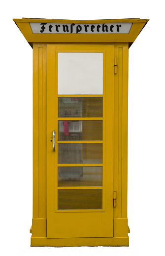 an isolated old yellow public telephone booth