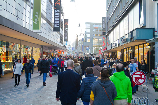 Stores and shopping people and crowd in Westenhellweg of Dortmund in autumn season. View over walking people. At left side is a Saturn store. People at any cosumer age are walking in street